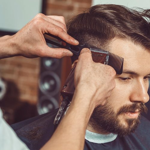 the-hands-of-young-barber-making-haircut-to-attractive-man-in-barbershop.jpg